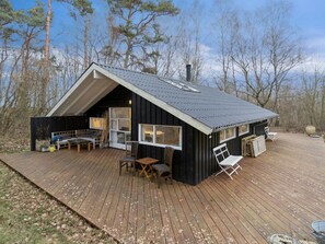 Eine Hütte mit geneigtem Dach, einer Terrasse und einem großen Fenster.