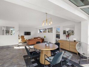 A modern interior with a round wooden dining table, black chairs, a sofa, and a white chair. - "Falk" - 900m from the sea by Interhome (Bindslev)