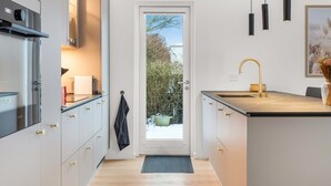 A modern kitchen with white cabinetry, a black countertop, and a gold faucet. - "Algut" - 80m from the sea by Interhome (Haderslev)