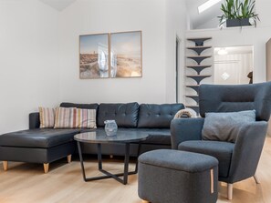 Ein modernes Wohnzimmer mit einer Eckcouch, einem runden Couchtisch und einem grauen Sessel.