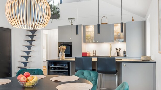 A modern kitchen with a central island, a dining area with teal chairs, and a large pendant light. - "Algut" - 80m from the sea by Interhome (Haderslev)