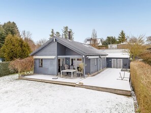 Ein zweistöckiges Haus mit überdachter Terrasse, Garage und umzäunter Garten.