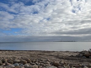 Ein Strand mit felsigem Ufer und einer fernen Insel.
