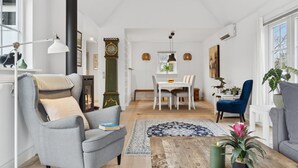 Een woonkamer met een bank, fauteuil, salontafel en een eethoek met tafel en stoelen.