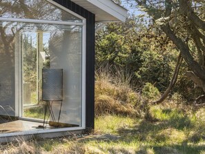 Ein modernes Haus mit einem großen Glasfenster, einer Metallskulptur und einer natürlichen Umgebung.