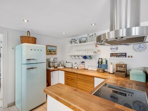 Una cocina con un refrigerador de estilo vintage, gabinetes de madera, horno empotrado y varios electrodomésticos.