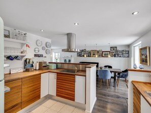 Una cocina moderna con armarios de madera, una isla central y una zona de comedor con una silla azul.