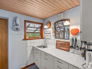 A kitchen with white cabinets, a wooden ceiling, a window with a view, and a clock on the wall. - "Saxe" - 1km from the sea by Interhome (Løkken)