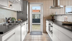 Een moderne keuken met witte kasten, een zwart aanrecht en uitzicht door een glazen deur.