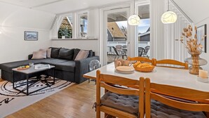 Un espacio habitable moderno con sofá, mesa de comedor, sillas y vistas al exterior.