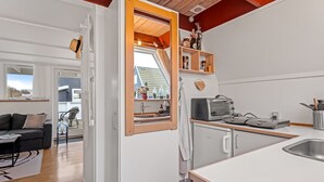 Cocina compacta con horno integrado, un lavamanos y ventana con vistas a una terraza.