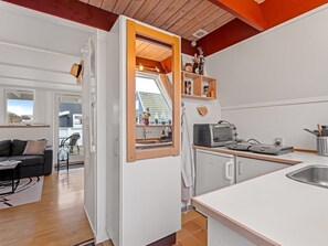 Une cuisine compacte dotée d’un four encastré, d’un évier et d’une fenêtre donnant sur une terrasse.