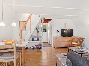 Un apartamento moderno con comedor, sala de estar, televisor y escalera.