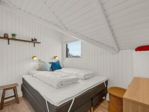 Ein Schlafzimmer mit einem Bett, Nachttischlampen, einem Fenster, einem kleinen Tisch und einem Regal mit Dekoration.