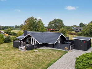 Une maison moderne avec un toit en pente, un patio couvert et une allée gravillonnée.