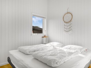 A bedroom with a bed, a window, a bedside table, and a dreamcatcher. - "Angelita" - 50m from the sea by Interhome (Sjølund)