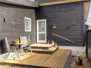 A modern house with a dark exterior, a front door, a small porch with a table and chairs, and a potted plant. - "Angelita" - 50m from the sea by Interhome (Sjølund)