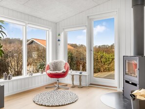 A room with a red chair, a round rug, a fireplace, and large windows. - "Angelita" - 50m from the sea by Interhome (Sjølund)