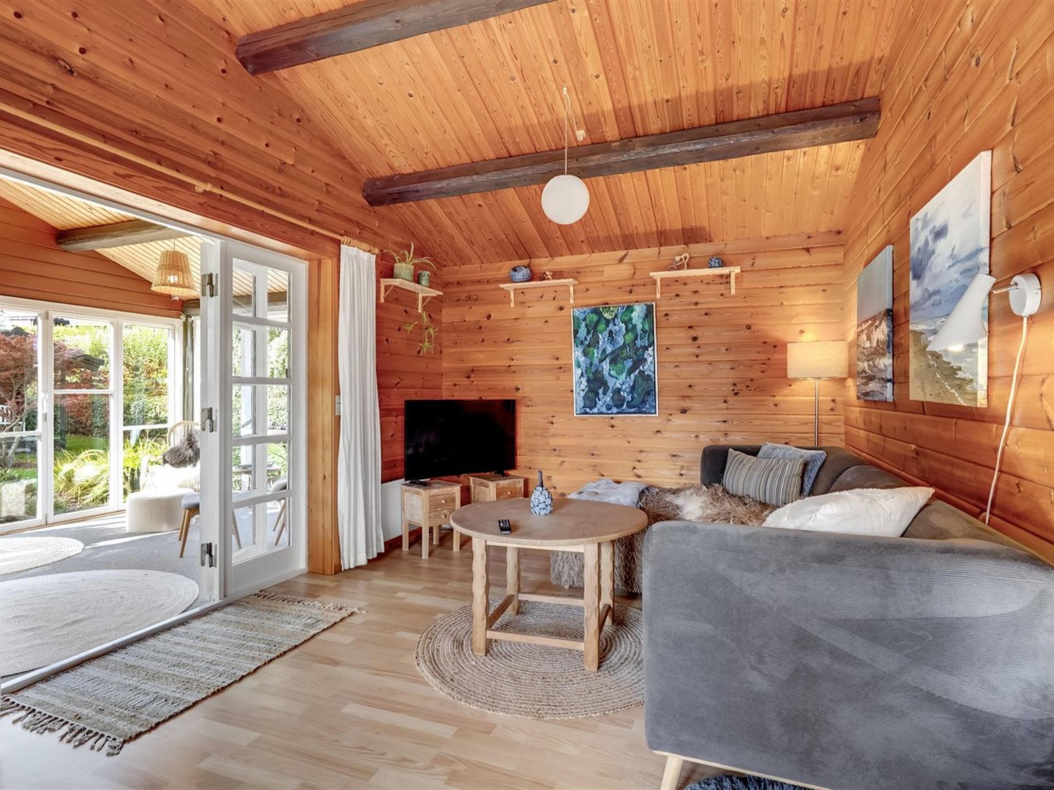 Ein Holzhütten-Interieur mit Fernseher, Sofa, Tisch und Bildern.