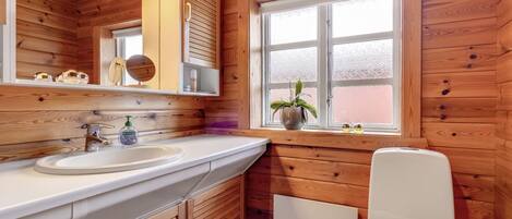 A wooden cabin bathroom with a sink, mirror, and toilet.