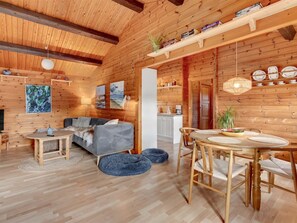 Un interno accogliente di una baita, con angolo salotto, zona pranzo e cucina.