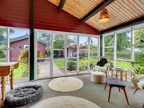 Una stanza luminosa con ampie finestre, soffitto in legno e vista su un giardino.