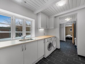 Eine moderne Küche mit Einbauwaschmaschine, Spüle und Fenster mit Ausblick.