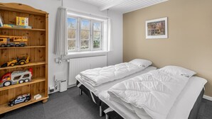 A bedroom with two beds, a wooden toy shelf, a window, a radiator, and a framed picture on the wall. - "Synnöve" - 1.7km to the fjord by Interhome (Tim)