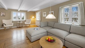 A modern living room with a sectional sofa, a round coffee table with fruit, a small side table, and two chairs. - "Synnöve" - 1.7km to the fjord by Interhome (Tim)