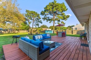 Eine Terrasse mit Gartenmöbeln, einem Grill und einem Pool im Hintergrund.