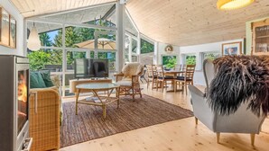 Ein modernes Wohnzimmer mit Kamin, großen Fenstern und einem Essbereich.