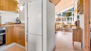 Eine moderne Küche mit Holzschränken, einem weißen Kühlschrank und einem Essbereich mit Blick.