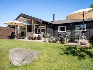 A modern house with a patio, outdoor furniture, and potted plants.