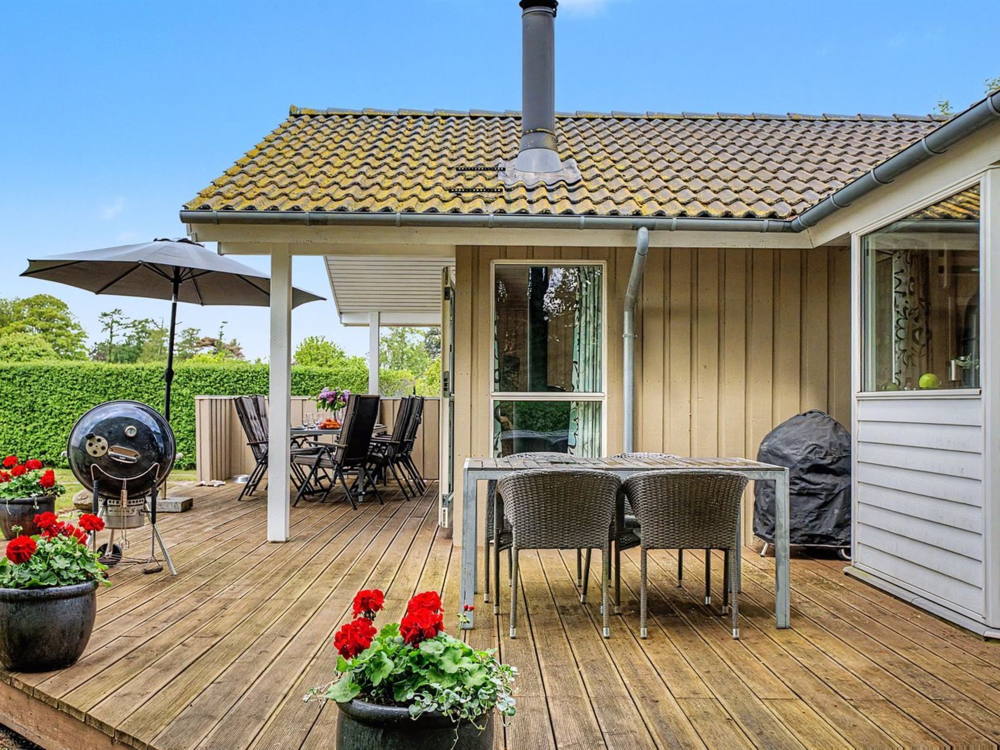 A covered outdoor patio with a grill, dining table, and chairs.