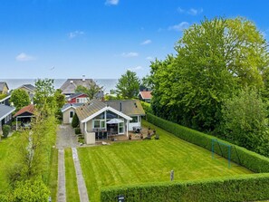 Ein Wohnhaus mit gepflegtem Rasen, einer Terrassenanlage und Meerblick.