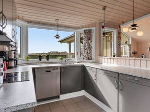 Eine moderne Küche mit Geschirrspüler, Spüle und Blick ins Freie.