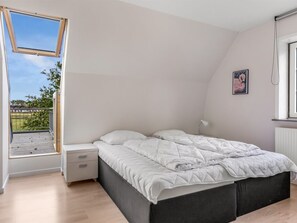 Ein Schlafzimmer mit Dachfenster, einem Bett, einem Nachttisch, einer Lampe und einem Poster an der Wand.