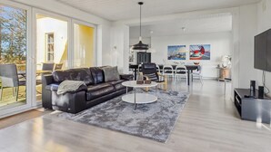 Un saló modern amb un sofà de cuir, una zona de menjador i una televisió.
