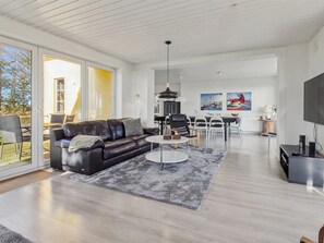 Ein modernes Wohnzimmer mit einer Ledersofa, einem Essbereich und einem Fernseher.