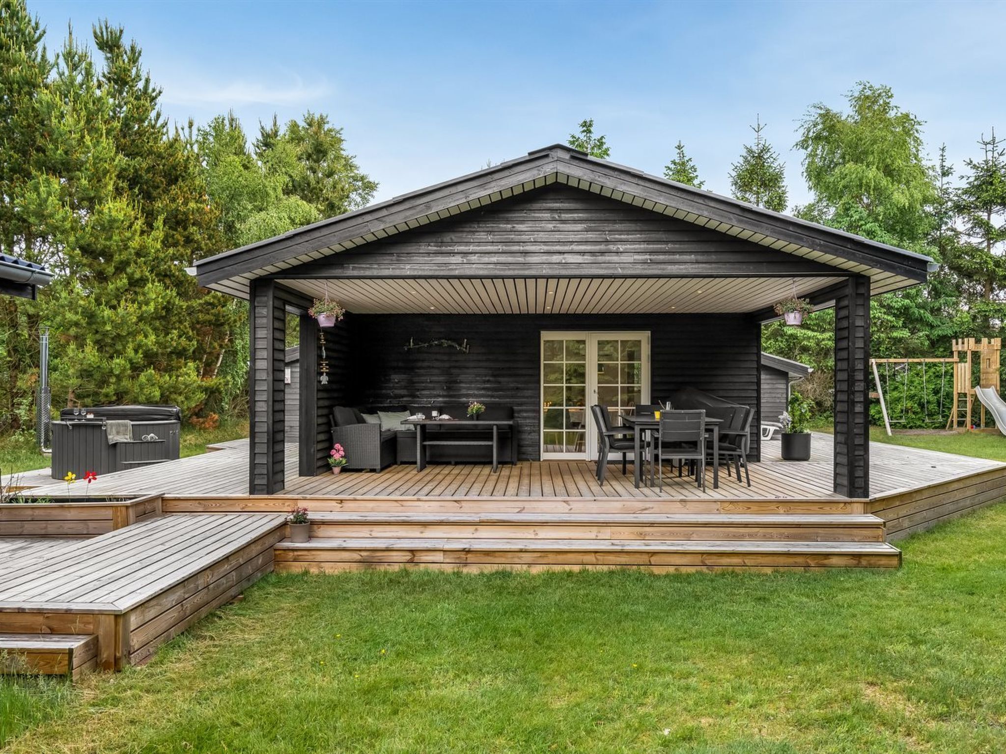 Een houten chalet met terras, buitenmeubels en een jacuzzi.