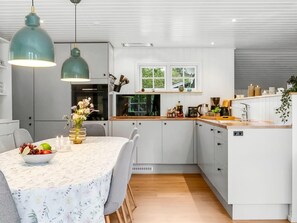 Eine moderne Küche mit weißen Schränken, einer Holz Arbeitsplatte und einem Essbereich mit Tisch für zwei Personen.