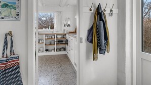 A kitchen with white cabinets, a hanging pot rack, and a window with a view of trees. - "Verene" - 725m from the sea by Interhome (Rudkøbing)