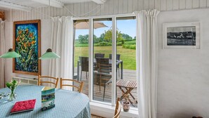 A dining area with a table, chairs, a painting, and a view of the outdoors. - "Verene" - 725m from the sea by Interhome (Rudkøbing)