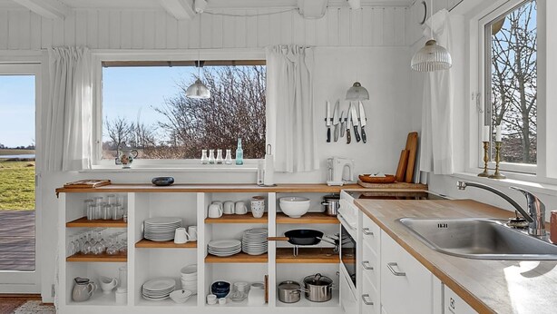 A modern kitchen with white cabinetry, a wooden countertop, and a large window offering a view of the outdoors. - "Verene" - 725m from the sea by Interhome (Rudkøbing)