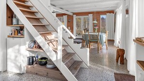 A staircase leading to a dining area with a table and chairs, a kitchen area with shelves and appliances, and a view of the outdoors. - "Verene" - 725m from the sea by Interhome (Rudkøbing)