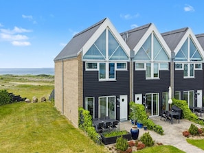 A modern building with a flat roof, large windows, and a patio area with outdoor seating.