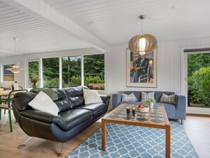 Ein modernes Wohnzimmer mit einem schwarzen Ledersofa, einem blauen Sofa, einem Holztisch und einem großen Gemälde an der Wand.