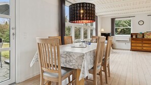 A dining area with a table, chairs, a chandelier, and a view through a glass door. - "Gittel" - 200m from the sea by Interhome (Rønne)