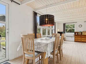 A dining area with a table, chairs, a chandelier, and a view through a glass door. - "Gittel" - 200m from the sea by Interhome (Rønne)