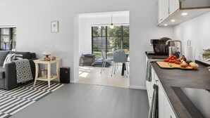 A modern kitchen with a dining area, a sofa, and a large window.